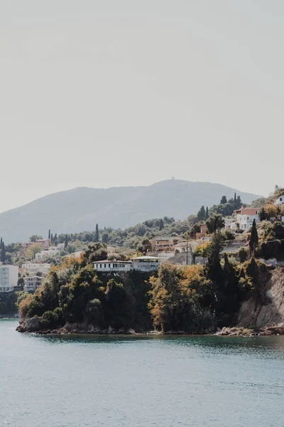 stock image Corfu, Greece. A hilly place by the water with residential houses and green trees. huge in the distance