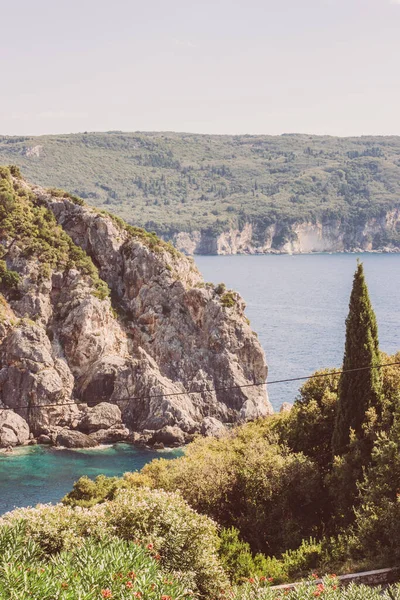 ギリシャのコルフ 緑の木々に覆われた青い水の中に巨大な山と灰色の岩の景色が美しい風景 — ストック写真