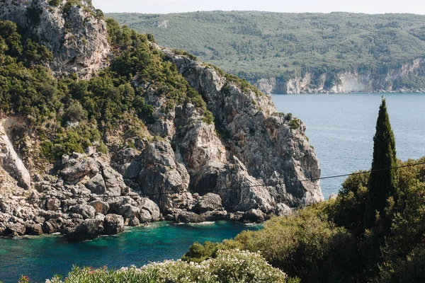 ギリシャのコルフ 緑の木々に覆われた青い水の中に巨大な山と灰色の岩の景色が美しい風景 — ストック写真