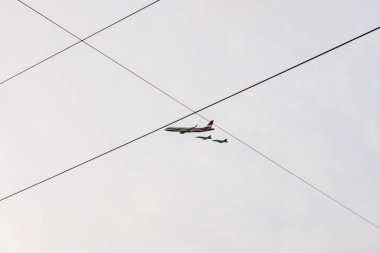 18.11.2022 Riga, Letonya. Letonya ulusal bayrağının renkleriyle süslenmiş bir AirBaltic uçağının gri sonbahar gökyüzünde dalgalandığı askeri geçit töreni ve onunla birlikte iki askeri uçak uçağı..