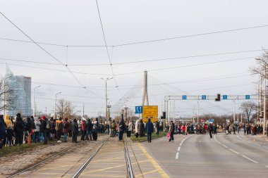 18.11.2022 Riga, Letonya. Letonya ulusal bayramında askeri geçit töreni. Bir grup insan sokakta durup askeri geçit törenini izliyor..