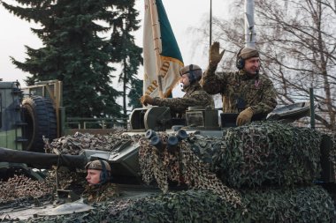 18.11.2022 Riga, Letonya. Ulusal tatillerde askeri geçit töreni. Askerler bir tankın içinde yol kenarındaki insanlara el sallıyor..