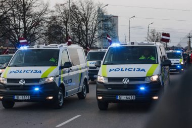 18.11.2022 Riga, Letonya. Askeri geçit töreni. Aydınlık mavi fenerli eyalet polis otobüsleri.