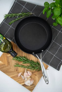 Empty cast iron frying pan on white culinary background, view from above
