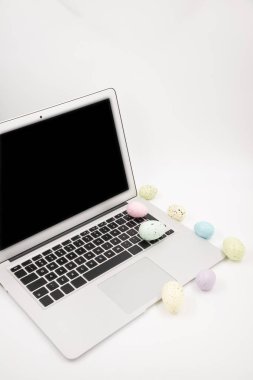 Paskalya yumurtalarının beyaz arka planında boş ekranı olan bilgisayar. Mesaj için yer var. Mutlu Paskalyalar! 