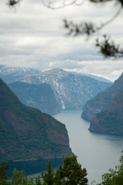 Stegastein 'in bakış açısından bulutlu bir yaz gününde Norveç dağlarının doğa manzarası. Dağlarda mavi UV radyasyonu.