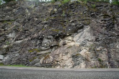 Bir dağ yolunun yanındaki kayalık dağ duvarında kaya güvenliği için metal bağlayıcılar delinmiş..