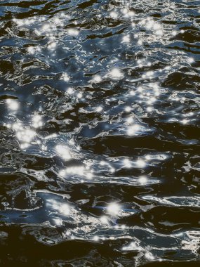 Mavi göl suyuna yakın çekim. Güzel bir yaz gününde yansıyan ve parıldayan dalgalar..