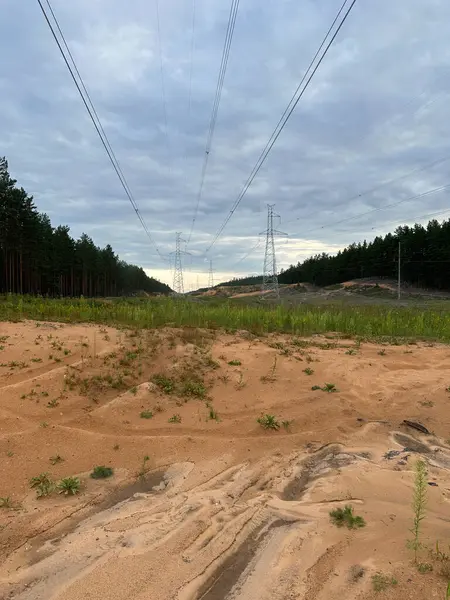 stock image Electric line with metal electricity poles and wires in a sandy quarry on a summer day under a blue sky.