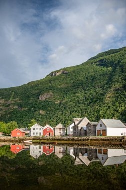 concrete bridge over a river with water like a mirror reflecting the beautiful Norwegian fjord mountains in the village of which is the administrative center in Vestland County, Norway. clipart