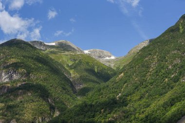Güneşli havada dağ sıralarında yeşil ağaçlarla muhteşem bir manzara. Norveç 'in konumu. Ekolojik olarak temiz bir bölge. Duvar kâğıdı. Toprağın güzelliğini keşfedin.