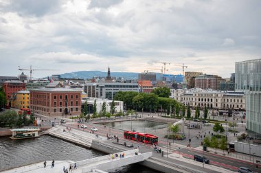 Oslo, Norveç - 12 Temmuz 2023 - Norveç şehir merkezi manzarası. İnşaat için görünen vinçleri olan binalar ve uzakta büyük bir dağ var..