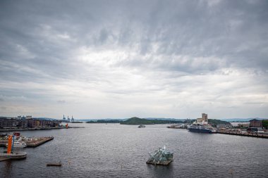 Oslo, Norveç - 12 Temmuz 2023 - Uzaktaki dağlarla Oslo liman iskelesi manzarası kasvetli, dramatik bir yaz günü.