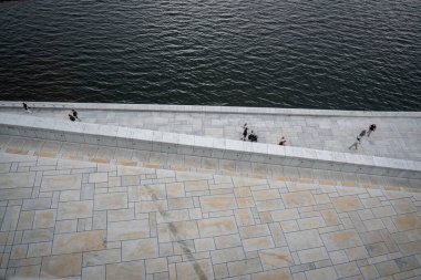 Oslo, Norveç - 12 Temmuz 2023 - Oslo Operası 'nın etrafında gün batımında yürüyen insanlar