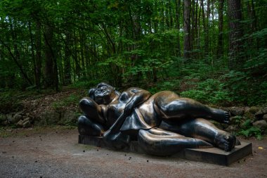 OSLO, NORWAY - JULY 12, 2023: Aluminum sculpture in Ekebergparken sculpture park. A woman lying on her side. clipart