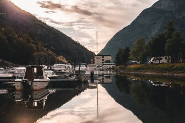 NORway - 7 Temmuz 2023: Tekne ve yat marinası köydeki dağların eteklerindeki nehirde .