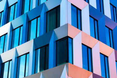 Geometrik Desenler, Mavi ve Sarı Paneller ve Güneş Işığı Yansımaları ile Soyut Modern Cephe