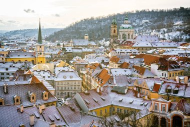 Scenic Winter View of Mal Strana in Prague with Snow-Covered Rooftops and St. Nicholas Church clipart