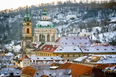 Scenic Winter View of Mal Strana in Prague with Snow-Covered Rooftops and St. Nicholas Church clipart