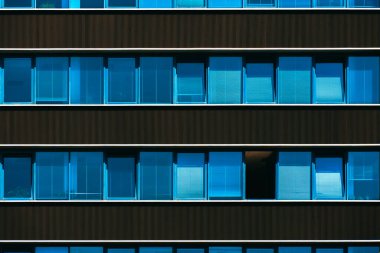 Tekrarlanan pencereler ve sıcak güneş ışığı aksanlarıyla simetrik ofis binası cephesi