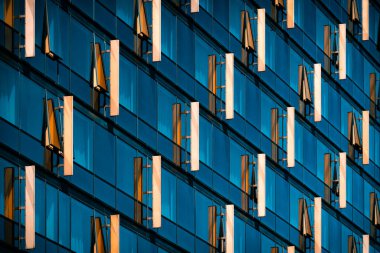 Yansıtıcı mavi pencereler ve dikey mimari elementlerin çapraz desenli cam cephe