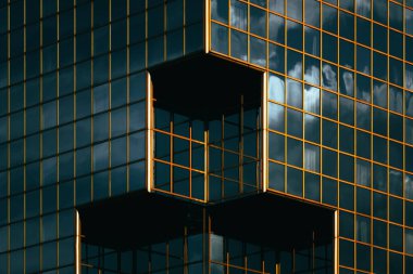 Derin yansımaları ve turuncu pencere ızgarası olan modern cam bina keskin bir geometrik bileşim oluşturuyor.