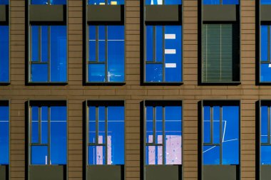 Tekrarlanan pencereler ve sıcak güneş ışığı aksanlarıyla simetrik ofis binası cephesi