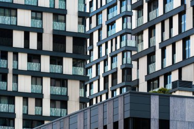 Beyaz ve siyah ızgaralı yüksek yoğunluklu konut binası ve dikey balkonları