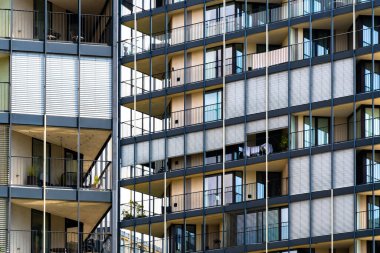 Kalın balkonları ve cam ve betondan ızgarası olan bir konut kulesi.