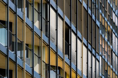 Kalın balkonları ve cam ve betondan ızgarası olan bir konut kulesi.