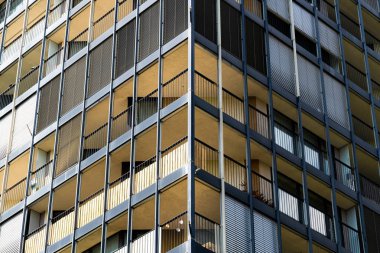 Kalın balkonları ve cam ve betondan ızgarası olan bir konut kulesi.