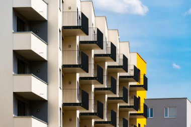 Soluk duvarları ve siyah metal balkonları olan modern apartman cephesi.