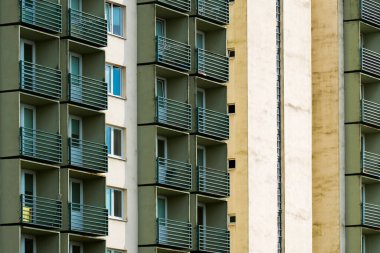 Tekrarlanan yeşil balkonları ve zıt soluk yüzeyleri olan eski tarz kule bloğu.