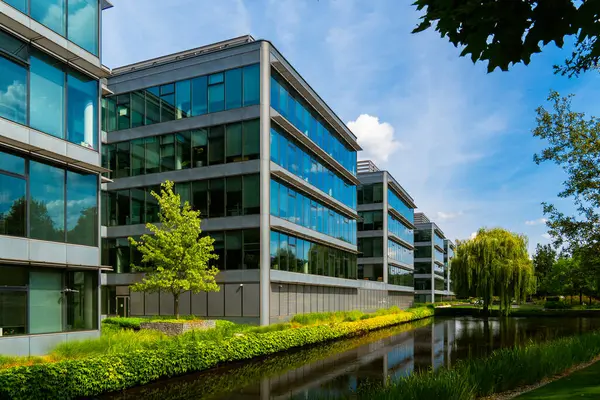 Yeşillik yansıması olan bir su özelliği boyunca ofis binaları