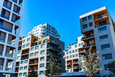 Canlı Yüzlü Modern Çok Katlı Konut Binası, Geniş Balkonlar ve Açık Mavi Gökyüzü Altında Görüntü Ufku