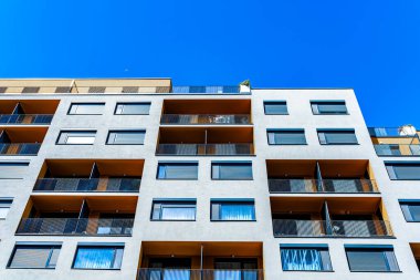 Canlı Yüzlü Modern Çok Katlı Konut Binası, Geniş Balkonlar ve Açık Mavi Gökyüzü Altında Görüntü Ufku