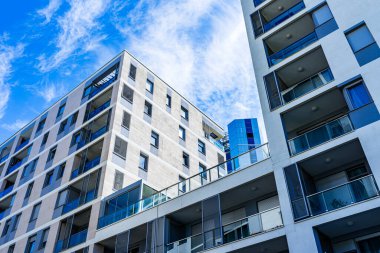 Canlı Yüzlü Modern Çok Katlı Konut Binası, Geniş Balkonlar ve Açık Mavi Gökyüzü Altında Görüntü Ufku