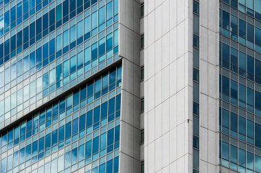 Izgara benzeri pencere bölümlerine sahip krema ve mavi cam cephe