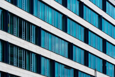 Izgara benzeri pencere bölümlerine sahip krema ve mavi cam cephe