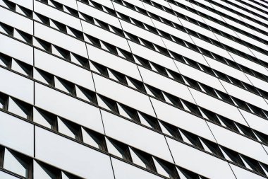 Modern geometrik çizgiler ve yansımalar içeren cam ve çelik ön cepheli çağdaş ofis binası