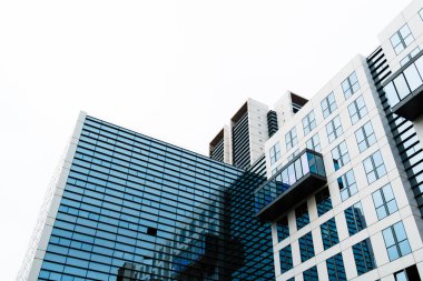 Modern geometrik çizgiler ve yansımalar içeren cam ve çelik ön cepheli çağdaş ofis binası