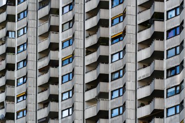 Çağdaş konut kulesinin geometrik cephesinde tekrarlanan balkonlar ve pencereler sarı aksanlı paneller yer almaktadır.