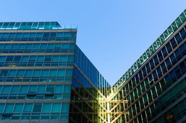Contemporary office building with metallic facade and geometric glass design under clear deep blue sky