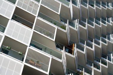 Modern residential architecture with repeating balconies and geometric facade under bright clear blue sky background