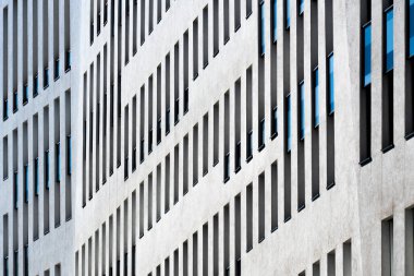 Contemporary office building with vertical window rhythm and clean white facade under clear bright blue sky