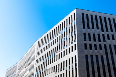 Contemporary office building with vertical window rhythm and clean white facade under clear bright blue sky