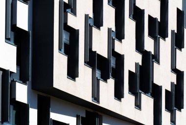 Modern office building with geometric black and white facade featuring irregular window pattern and strong contrast