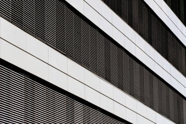 Modern architectural facade with horizontal metal louvers and reflective panels creating clean geometric rhythm and symmetry