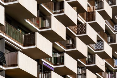 Modern residential building with projecting concrete balconies and minimalist geometric design emphasizing urban architectural rhythm
