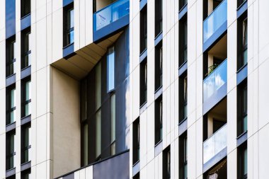 Contemporary office building with vertical window rhythm and clean white facade under clear bright blue sky